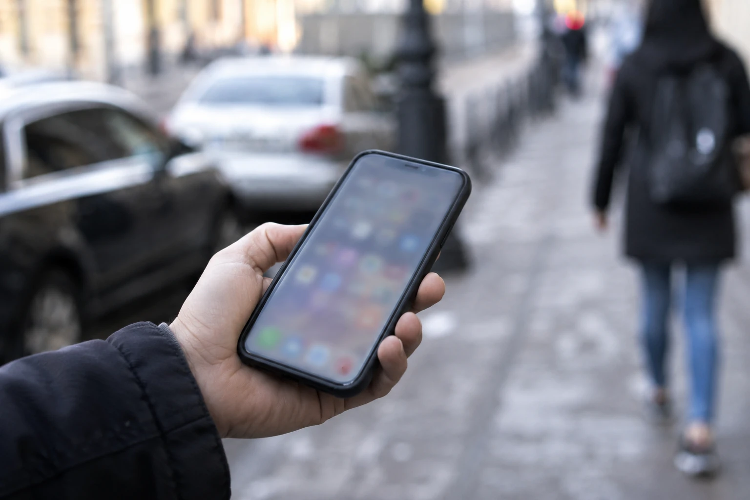 Ruka drži mobitel s nečitljivim zaslonom na ulici